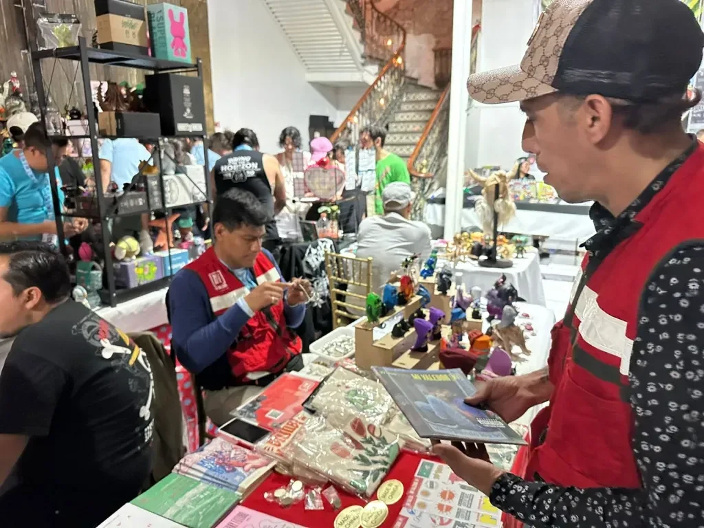Personas recorriendo un stand con publicaciones, piezas y objetos de colección durante la feria