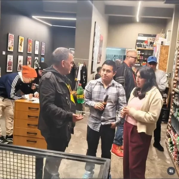 Tres personas conversando en una tienda rodeadas de exhibidores y piezas de colección